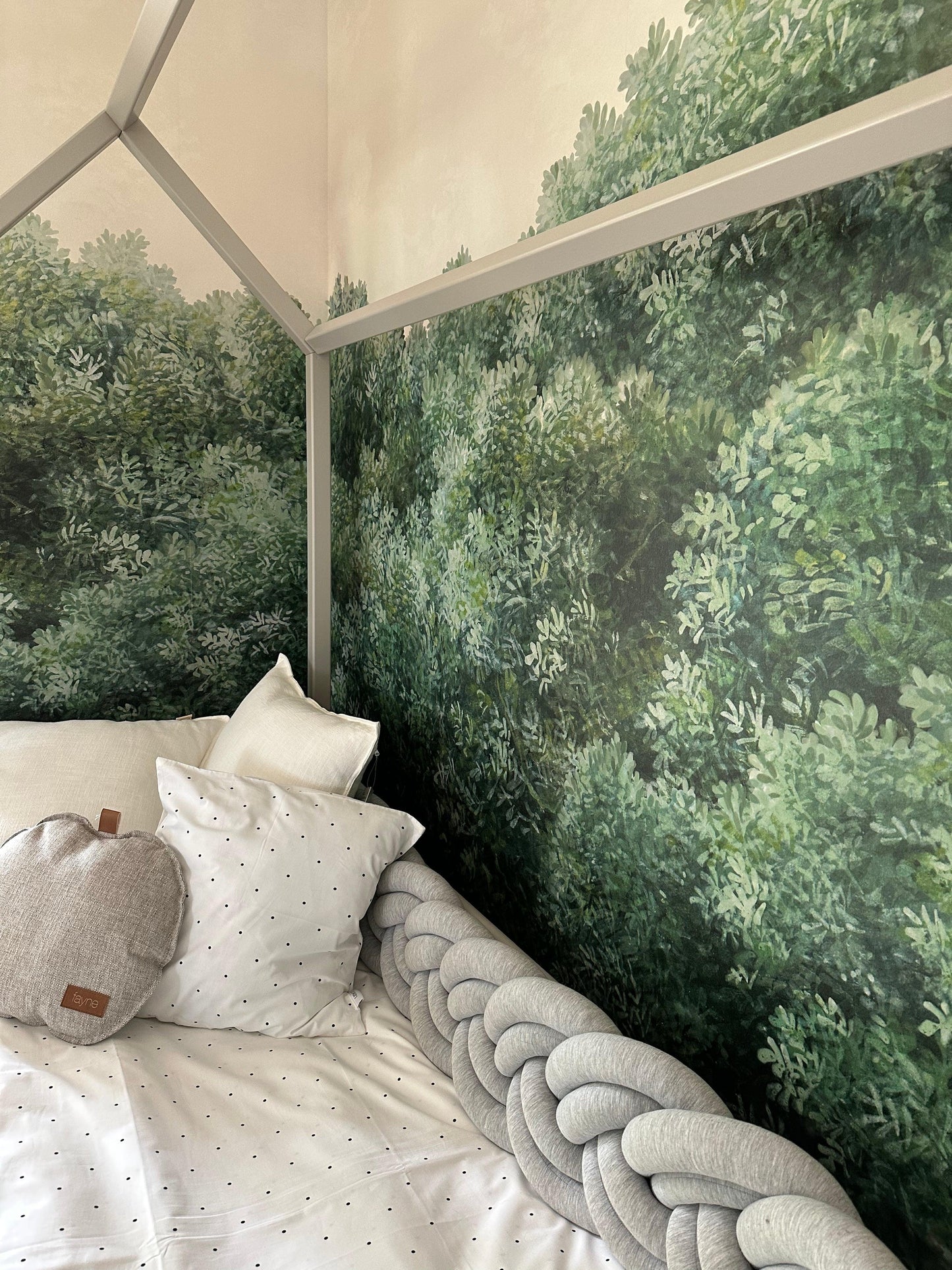 house bed in dove grey with textiles in a in a room with tree patterned wallpaper