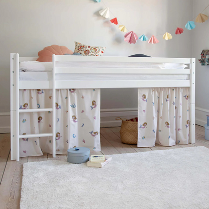 White children's bed with patterned curtains in a room with toys and decorations.