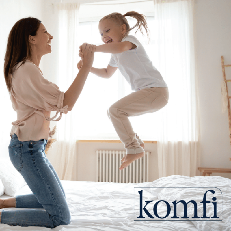 Woman and child playing on a bed with 'komfi' logo in the corner