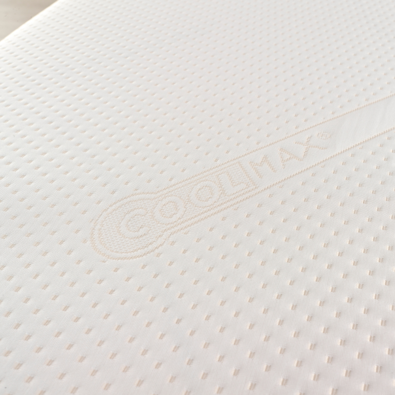 Close-up of a white mattress with a brand logo on a light background