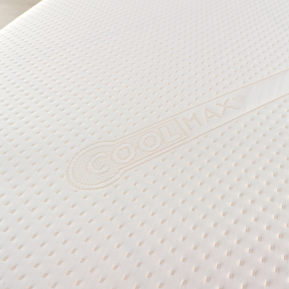 Close-up of a white mattress with a brand logo on a light background