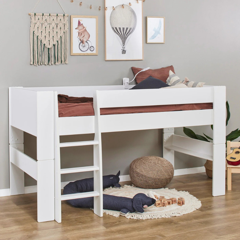 White children's bed with wooden slats in a room with toys and decor.