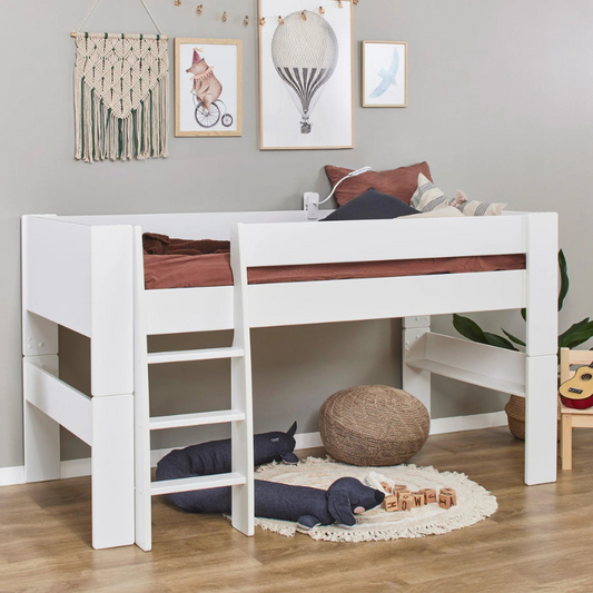 White children's bed with wooden slats in a room with toys and decor.